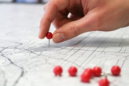 Hand mit Pins auf Landkarte